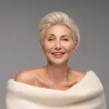 Elegancka kobieta po 50-tce z krótką, blond fryzurą. Inspiracja dla pań szukających stylowych fryzur.