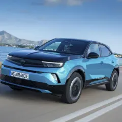 Niebieski Opel Mokka z czarnym dachem jedzie wzdłuż wybrzeża. Kolor mokka idealnie pasowałby do tej scenerii.