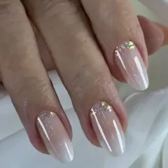 Eleganckie paznokcie hybrydowe w stylu babyboomer z subtelnymi drobinkami brokatu przy skórkach.