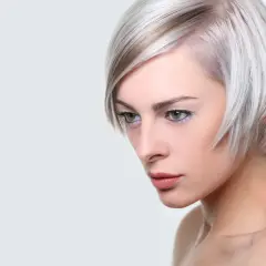 Kobieta z platynowym blond włosami, ułożonymi w nowoczesną fryzurę na pazia, z subtelnym makijażem.
