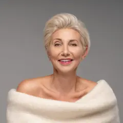 Elegancka kobieta po 50-tce z krótką, blond fryzurą. Inspiracja dla pań szukających stylowych fryzur.