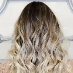 Piękne, falowane włosy z efektem ombre blond, przechodzące od ciemnego brązu do jasnego blondu.