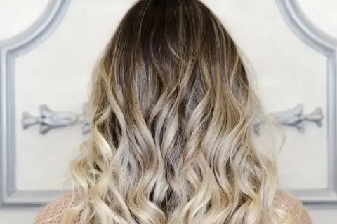 Piękne, falowane włosy z efektem ombre blond, przechodzące od ciemnego brązu do jasnego blondu.