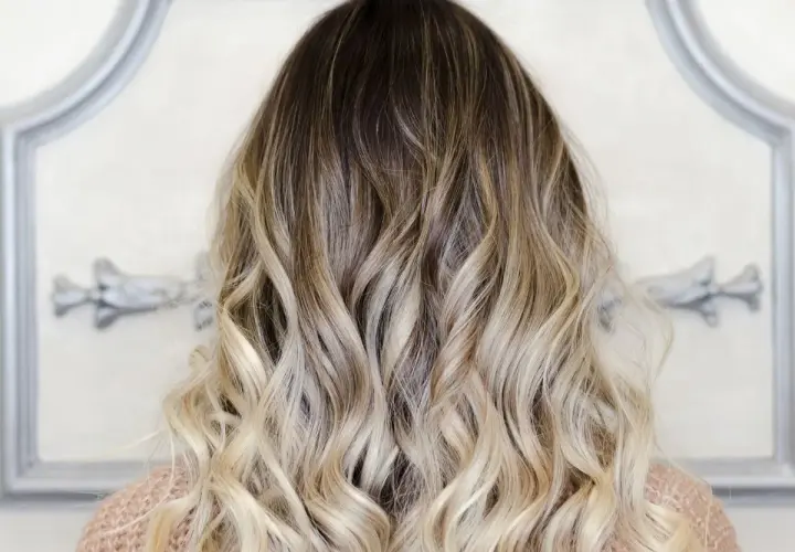 Piękne, falowane włosy z efektem ombre blond, przechodzące od ciemnego brązu do jasnego blondu.