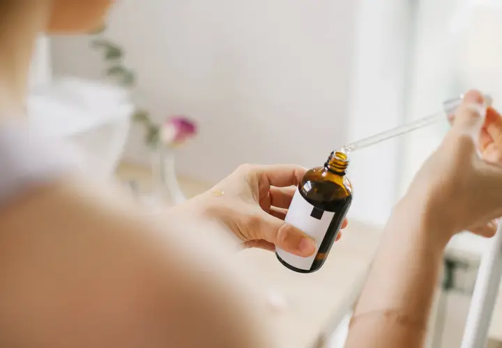 Kobieta aplikuje serum z pipetką na dłoń. Bezpieczny niacynamid w ciąży to dobry wybór dla delikatnej skóry.