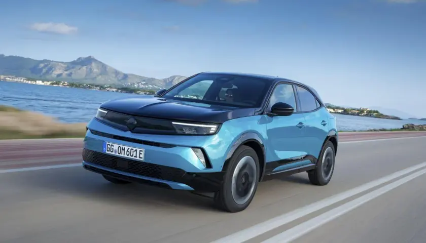 Niebieski Opel Mokka z czarnym dachem jedzie wzdłuż wybrzeża. Kolor mokka idealnie pasowałby do tej scenerii.