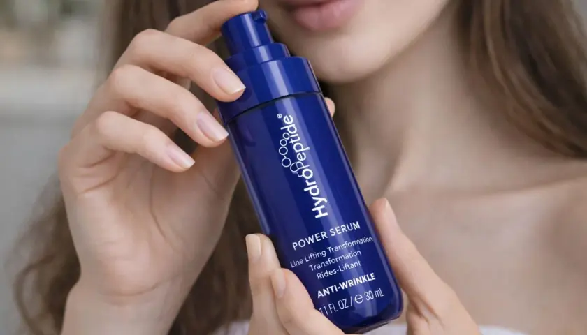 Kwas hialuronowy w serum HydroPeptide. Jak stosować? Delikatne dłonie trzymają buteleczkę z pompką, gotową do aplikacji.