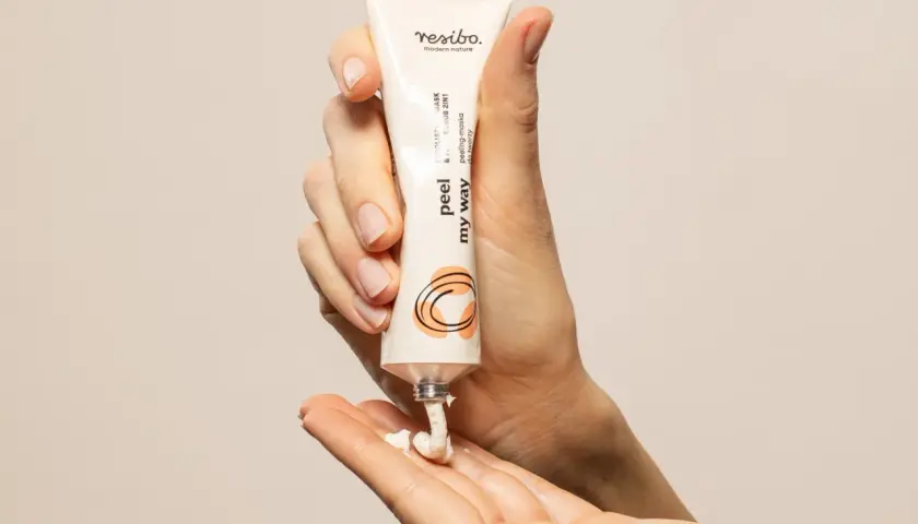Dłonie aplikują peeling do twarzy Resibo. Delikatna eksfoliacja dla promiennej cery.