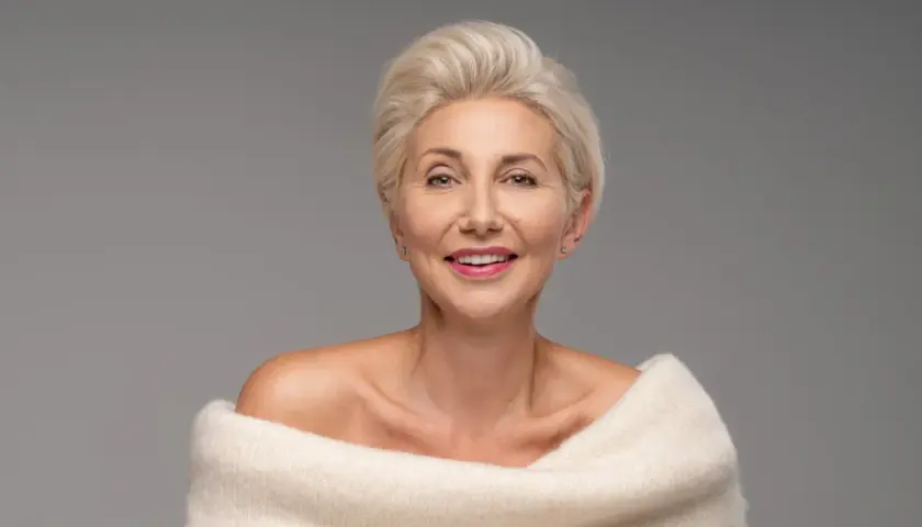 Elegancka kobieta po 50-tce z krótką, blond fryzurą. Inspiracja dla pań szukających stylowych fryzur.