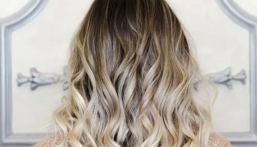 Piękne, falowane włosy z efektem ombre blond, przechodzące od ciemnego brązu do jasnego blondu.