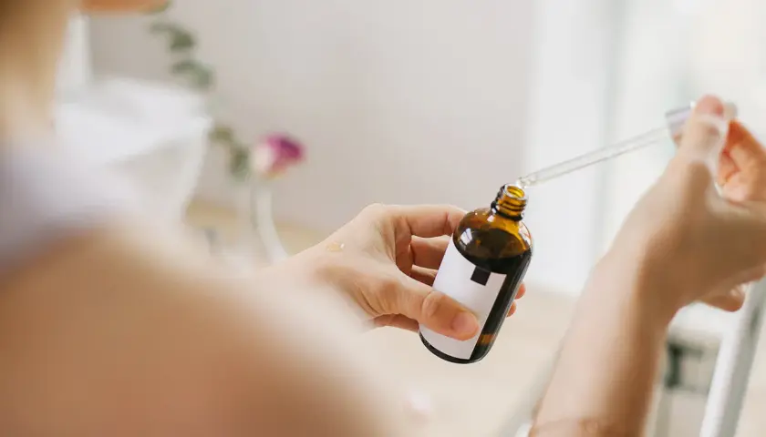 Kobieta aplikuje serum z pipetką na dłoń. Bezpieczny niacynamid w ciąży to dobry wybór dla delikatnej skóry.