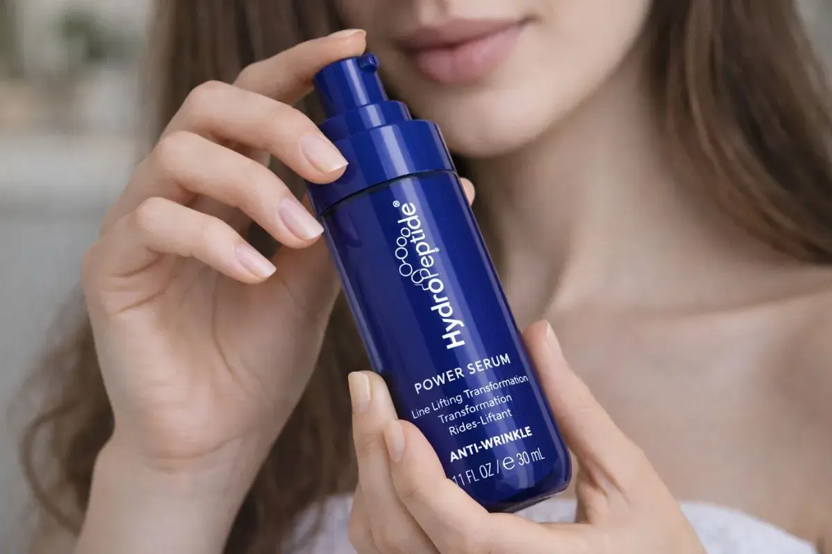 Kwas hialuronowy w serum HydroPeptide. Jak stosować? Delikatne dłonie trzymają buteleczkę z pompką, gotową do aplikacji.