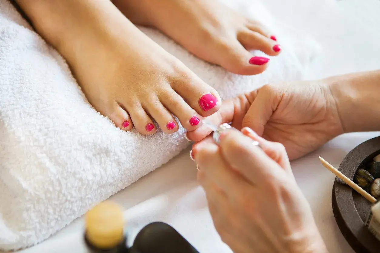 Piękne, różowe pedicure paznokcie u nóg są dopracowywane przez kosmetyczkę.
