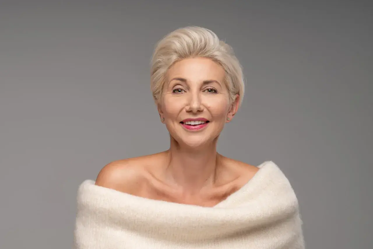Elegancka kobieta po 50-tce z krótką, blond fryzurą. Inspiracja dla pań szukających stylowych fryzur.