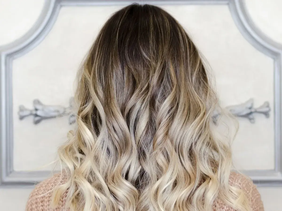 Piękne, falowane włosy z efektem ombre blond, przechodzące od ciemnego brązu do jasnego blondu.