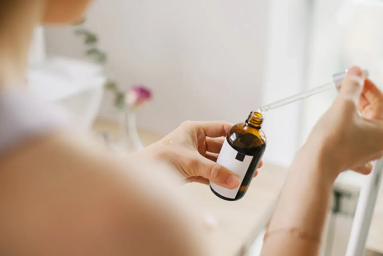 Kobieta aplikuje serum z pipetką na dłoń. Bezpieczny niacynamid w ciąży to dobry wybór dla delikatnej skóry.