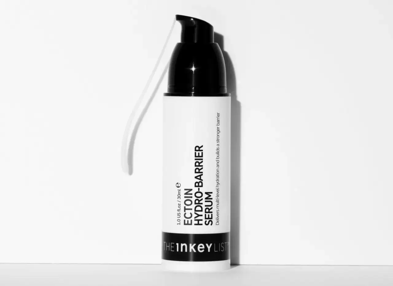Biała butelka z czarną pompką, zawierająca serum z ektoiną. Produkt zapewnia nawilżenie i wzmacnia barierę skórną.