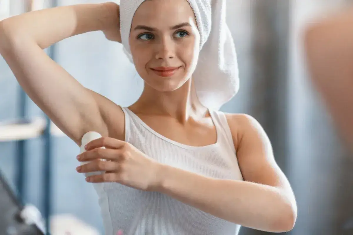 Kobieta z ręcznikiem na głowie aplikuje antyperspirant. Składnik chlorek glinu zapewnia skuteczną ochronę.