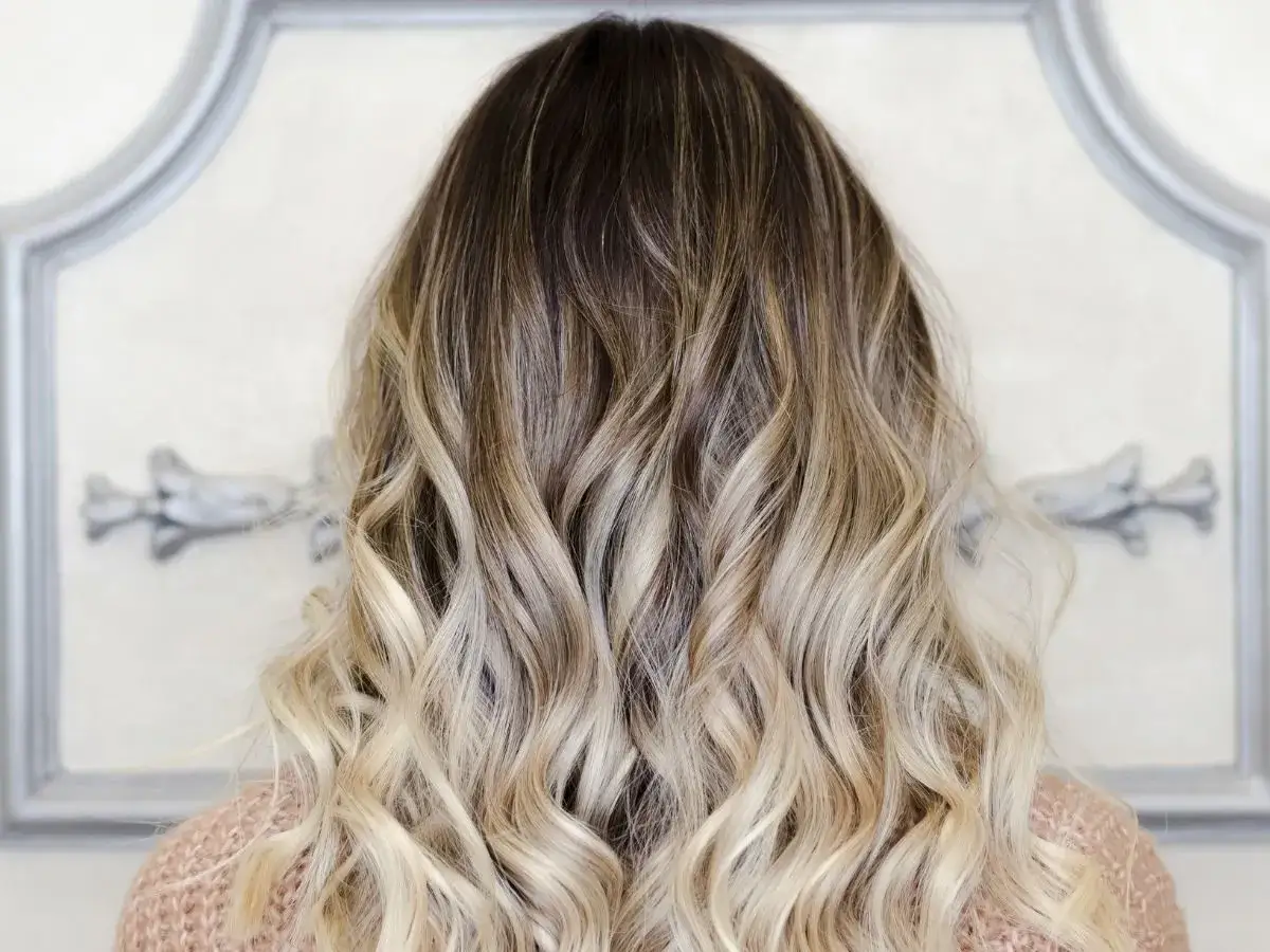 Piękne ombre włosy, od ciemnego brązu po jasny blond, delikatnie pofalowane.