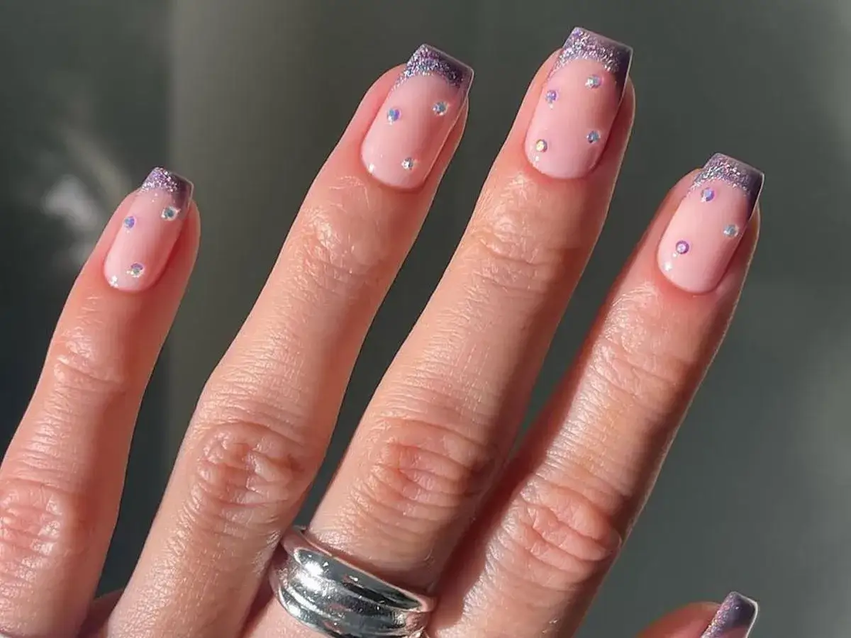 Krótki french z brokatowym ombre i błyszczącymi kamyczkami. Delikatny róż i fiolet tworzą subtelny, ale efektowny manicure.