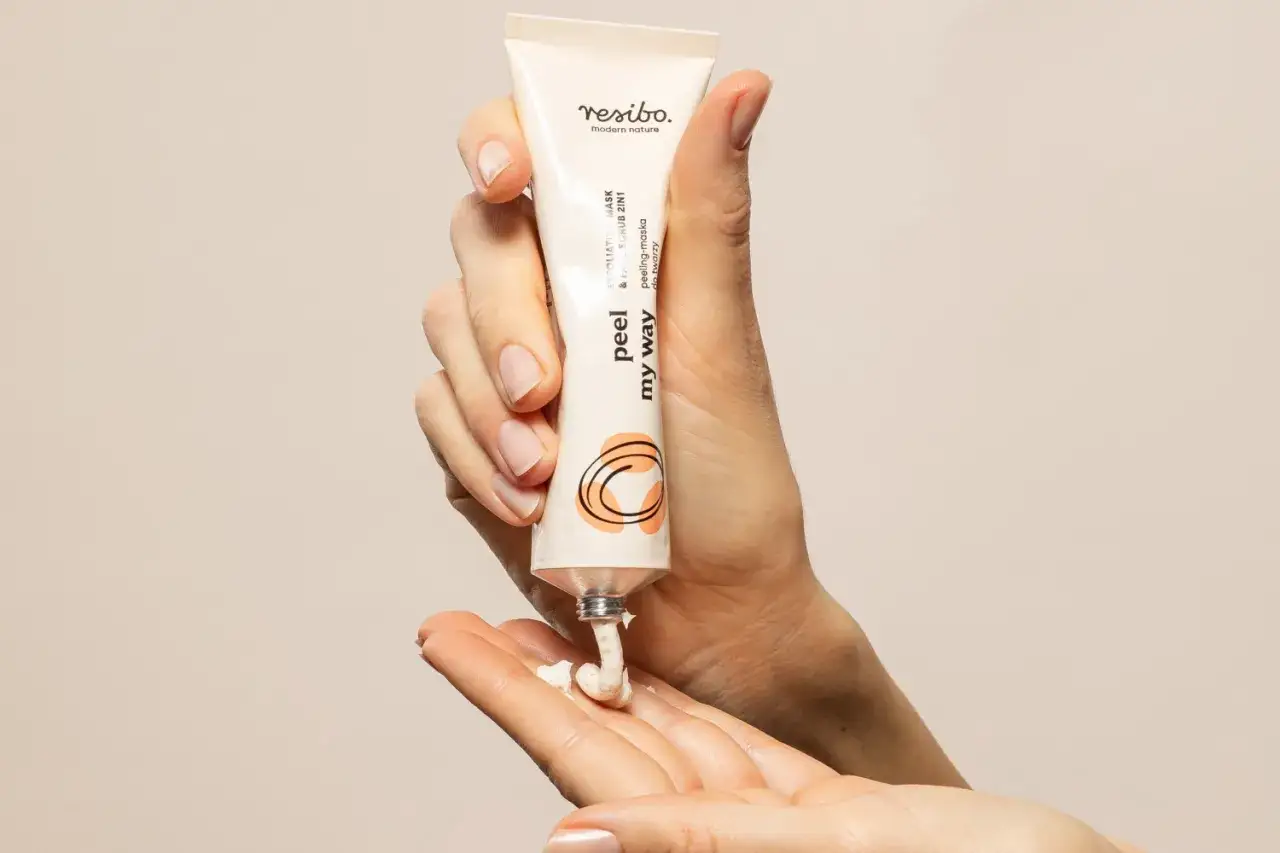 Dłonie aplikują peeling Resibo, który zapewnia delikatną eksfoliację.