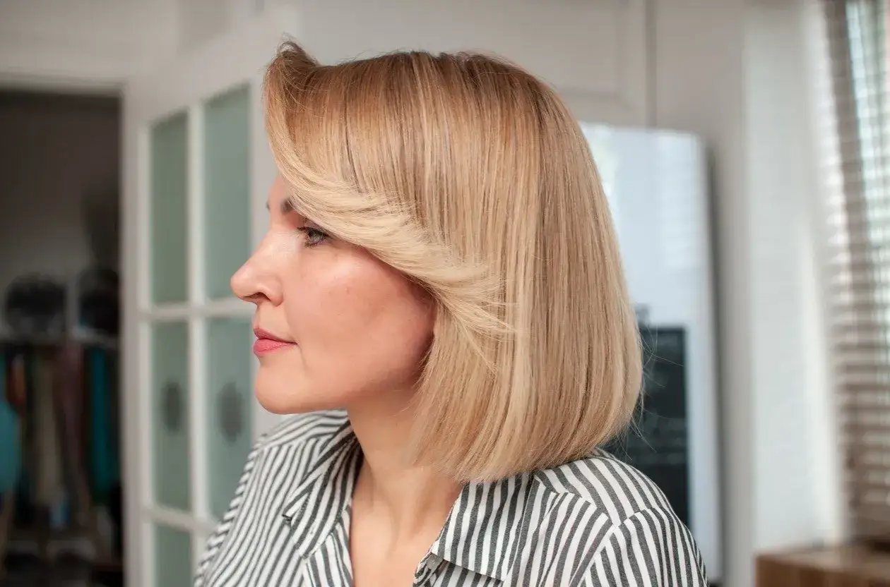 Kobieta z blond bobem i stylową grzywką, w paski.